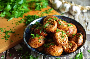 Grilled mushrooms with parsley in a blue bowl on a wooden background
