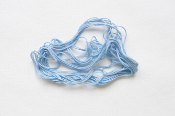Tangled blue thread on white background.