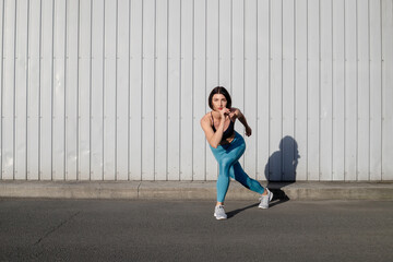Portrait of sportswoman smiling outdoors in morning. Female in running outfit standing outdoors in city.