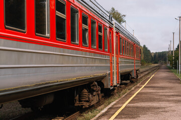 Obraz premium Red passenger commuter train at the railway platform with vintage toning. Railway station. Travel. Train
