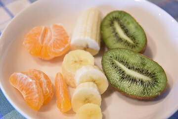 Fresh Peeled Banana, Kiwi and Orange in the Plate