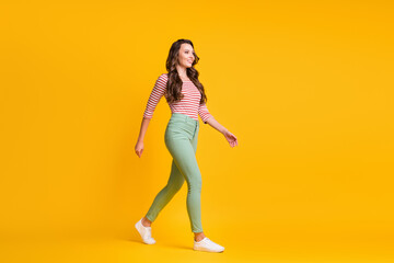 Fototapeta na wymiar Full length body size side profile photo of girl with curly hair going fast smiling isolated on vibrant yellow color background