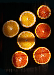 Tasty sliced oranges on the black wooden table 