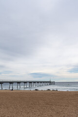Fototapeta premium Angular view of footbridge over beach and sea, on a cloudy day, in Badalona, Catalonia, Spain, in vertical