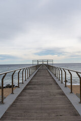 Fototapeta na wymiar Perspective of footbridge over beach and sea, a cloudy day, in Badalona, Catalonia, Spain, in vertical