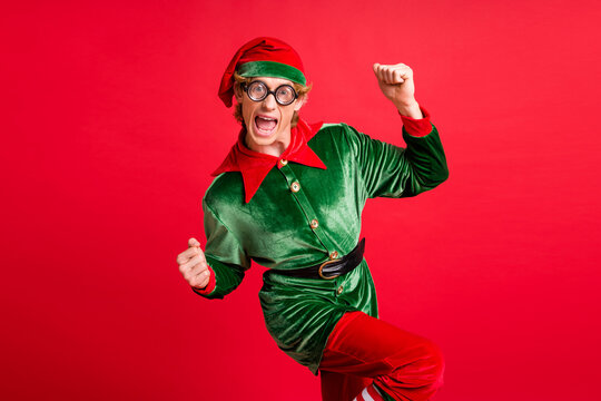 Photo of ecstatic little fairy x-mas elf raise fists wear headwear costume isolated over shine red color background