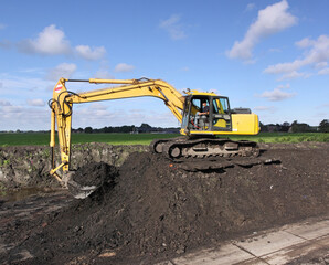 Obraz premium A crane filling a trailer with ripened dredging spoil from a storage compartment 