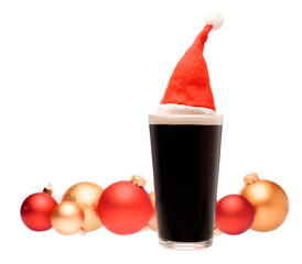 Dark ale beer in pint glass with christmas red hat and christmas baubles in background on white