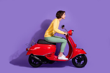 Fototapeta na wymiar Full length body size side profile photo of young girl wearing casual outfit driving red motorcycle smiling looking forward isolated on vivid purple color background