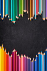 Wave border of colorful wooden pencils on a blank blackboard, back to school concept, vertical.