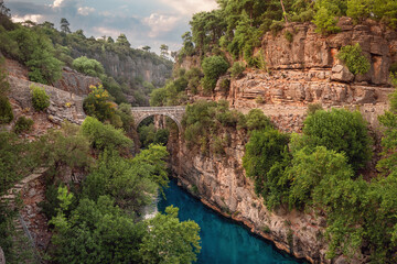 Ancient arch bridge over the Koprucay river gorge in Koprulu national Park in Turkey. Panoramic scenic view of the canyon and blue stormy mountain river