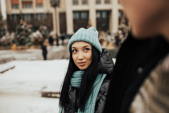 Close-up of smiling girl wearing warm clothes and are walking with her boyfriend. Cropped photo. 