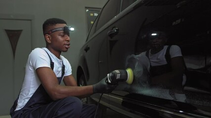 A young African-American polishes a car.Car detailing - Men are using machinery car polishers maintenance to remove marks repair according to the surface of the car's paint before continuing to coat - Powered by Adobe
