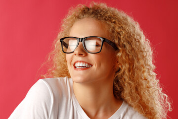 Joyful young curly woman in glasses smiling