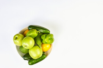 A bowl full of raw organic vegetables and fruits on white background with copy space