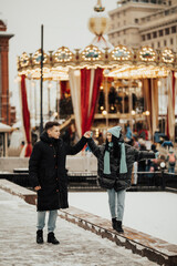 Fototapeta na wymiar Young romantic couple is having fun outdoors in winter in the amusement park.