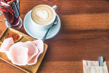 A Cup of coffee, a heart made of coffee foam. Coffee in a white Cup with a spoon in a cafe is on the table. Chips, a glass of mulled wine.