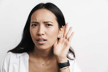 Displeased asian woman overhearing while posing at camera