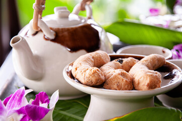 Afternoon tea in ceramic pot and butter cookies among flower