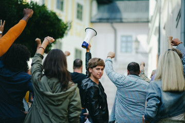 Portrait of woman with megaphone protesting on streets, strike and demonstration concept.