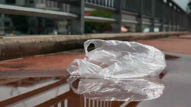 A discarded transparent plastic bag on a wet pavement