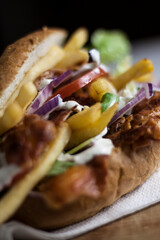 Fresh kebab burger with fries, salad, red onion, tomatoes and sauce