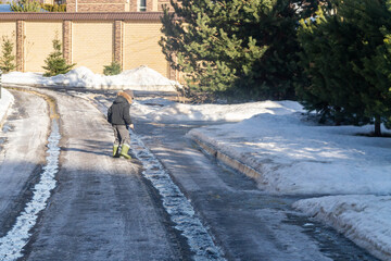 A boy walks along the road in the spring. Snow melts, streams flow.
