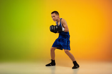Fototapeta na wymiar Winner. Teenage professional boxer training in action, motion isolated on gradient background in neon light. Kicking, boxing. Concept of sport, movement, energy and dynamic, healthy lifestyle.