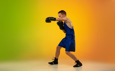 Winner. Teenage professional boxer training in action, motion isolated on gradient background in neon light. Kicking, boxing. Concept of sport, movement, energy and dynamic, healthy lifestyle.