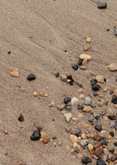 Different texture on the beach - water and sand, stones and pebbles, waves and splashes.