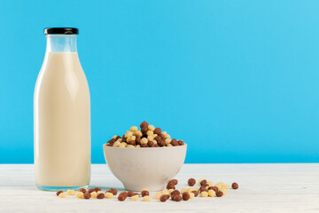 Breakfast cereal balls and milk in glass against blue background