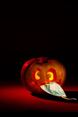 Halloween pumpkin with crazy face eating a mask. Dark orange and red tones. Vertical