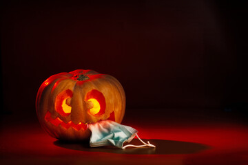 Halloween pumpkin with crazy face eating a mask. Dark orange and red tones