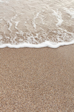 Different texture on the beach - water and sand, stones and pebbles, waves and splashes.