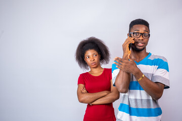 african woman feeling jealous, standing behind and listening to a man making a phone call