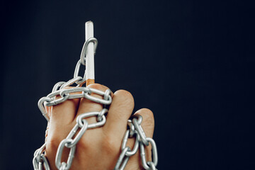 Male hand in metal chains holding cigarette
