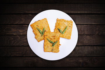 Three tempeh, fried flour with chilies served on a white plate. Top view.
