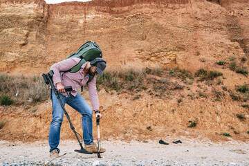 Man with metal detector searching for lost treasures on the beach