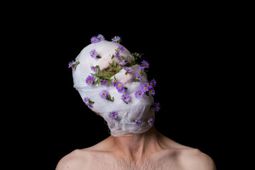 a portrait of a guy his head is wrapped in a bandage, flowers stick out of the bandage
