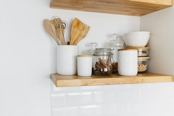 Kitchen shelves with various white ceramic and glass jars.