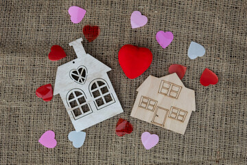 On a jute background, there are two models of the house. Multi-colored paper hearts are scattered around.