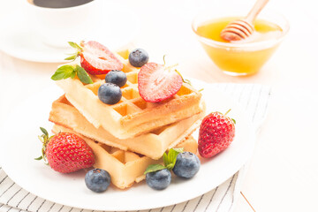 Fresh homemade food of berry Belgian waffles with honey, chocolate, strawberry, blueberry, maple syrup and cream. Healthy dessert breakfast concept with juice