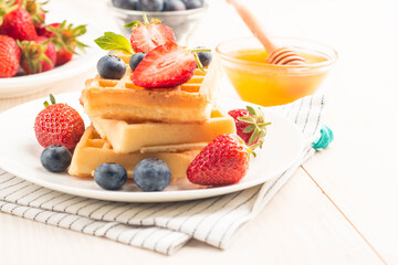 Fresh homemade food of berry Belgian waffles with honey, chocolate, strawberry, blueberry, maple syrup and cream. Healthy dessert breakfast concept with juice