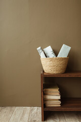 Handmade paper gift boxes in straw basket on wooden stand with books. Minimalist interior design concept.