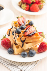 Fresh homemade food of berry Belgian waffles with honey, chocolate, strawberry, blueberry, maple syrup and cream. Healthy dessert breakfast concept with juice