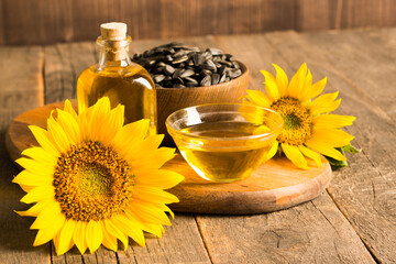 Closeup photo of sunflower oil with seeds on wooden background. Bio and organic product concept.