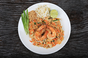 An overhead photo of a Shrimp Pad Thai, traditional Thai dish with stir fried rice noodles, shot from above on a rustic texture 