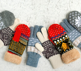 Bright mittens and gloves on a textured background. Gloves and mittens for autumn and winter. Warm knitted clothes for cold seasons. There is space for text.