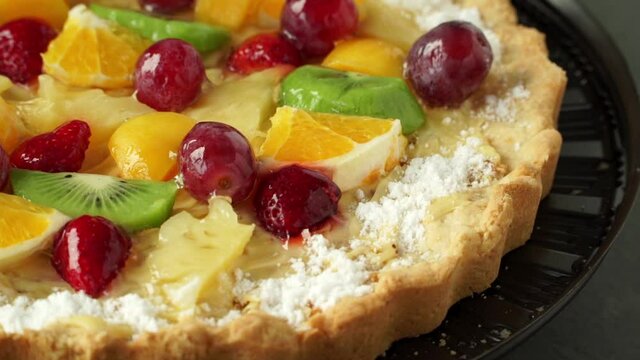 Close up of cake with fresh fruit and berries with cream rotates on tray. Holiday treat. Food dessert background. Bakery and pastry shop concept