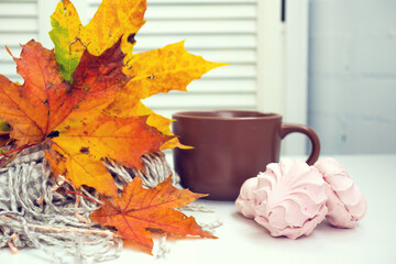 Autumn still life, a Cup of tea with yellow autumn leaves and a warm scarf on a light background, creative blur